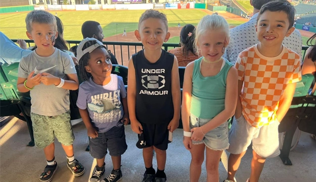 Six young children standing together indoors at a pediatric dental office event or celebration.
