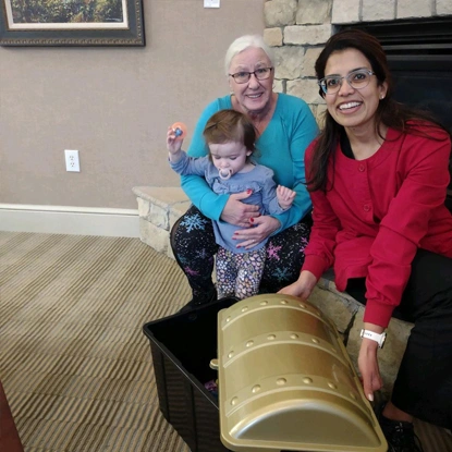 Three people and young child smile while examining large yellow dental model in office setting.
