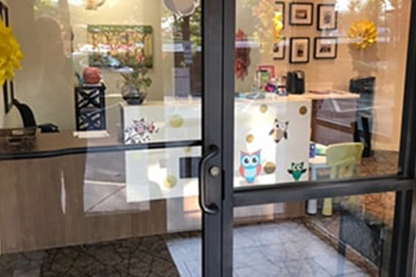 Pediatric dental office storefront entrance with welcoming window display and interior waiting area visible.