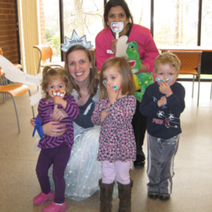 Pediatric dentist with four young children wearing party hats in dental office setting.