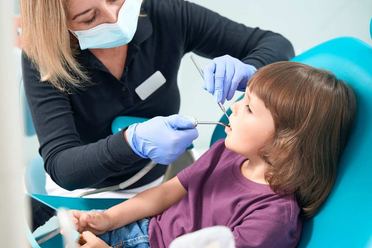 Pediatric dentist examining child's teeth during dental visit in Greensboro, NC.