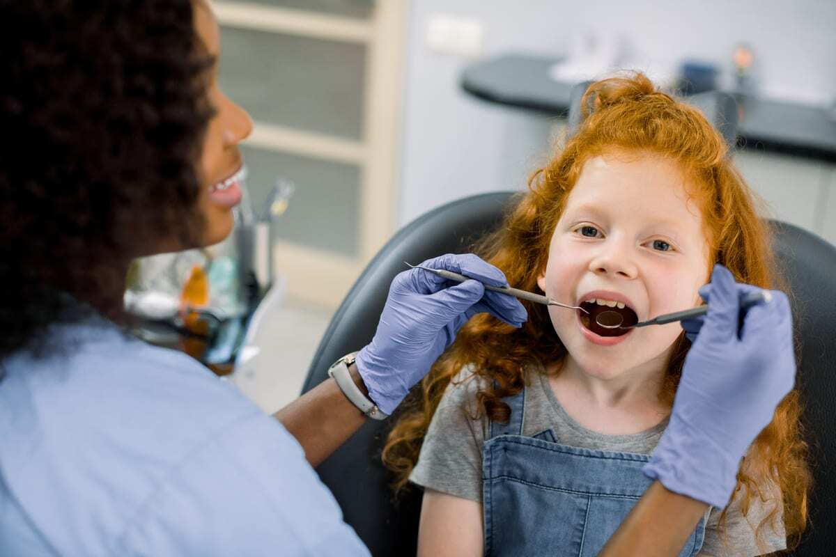 Young girl with red hair smiling during dental examination in Greensboro dental office.